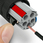 A hand is inserting a copper wire into a gray field wire-able connector with cage clamps for terminating ends of NMEA2000 cables.